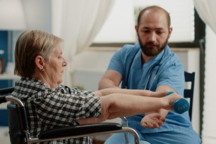 Nurse assisting disabled patient with physical exercises for recovery