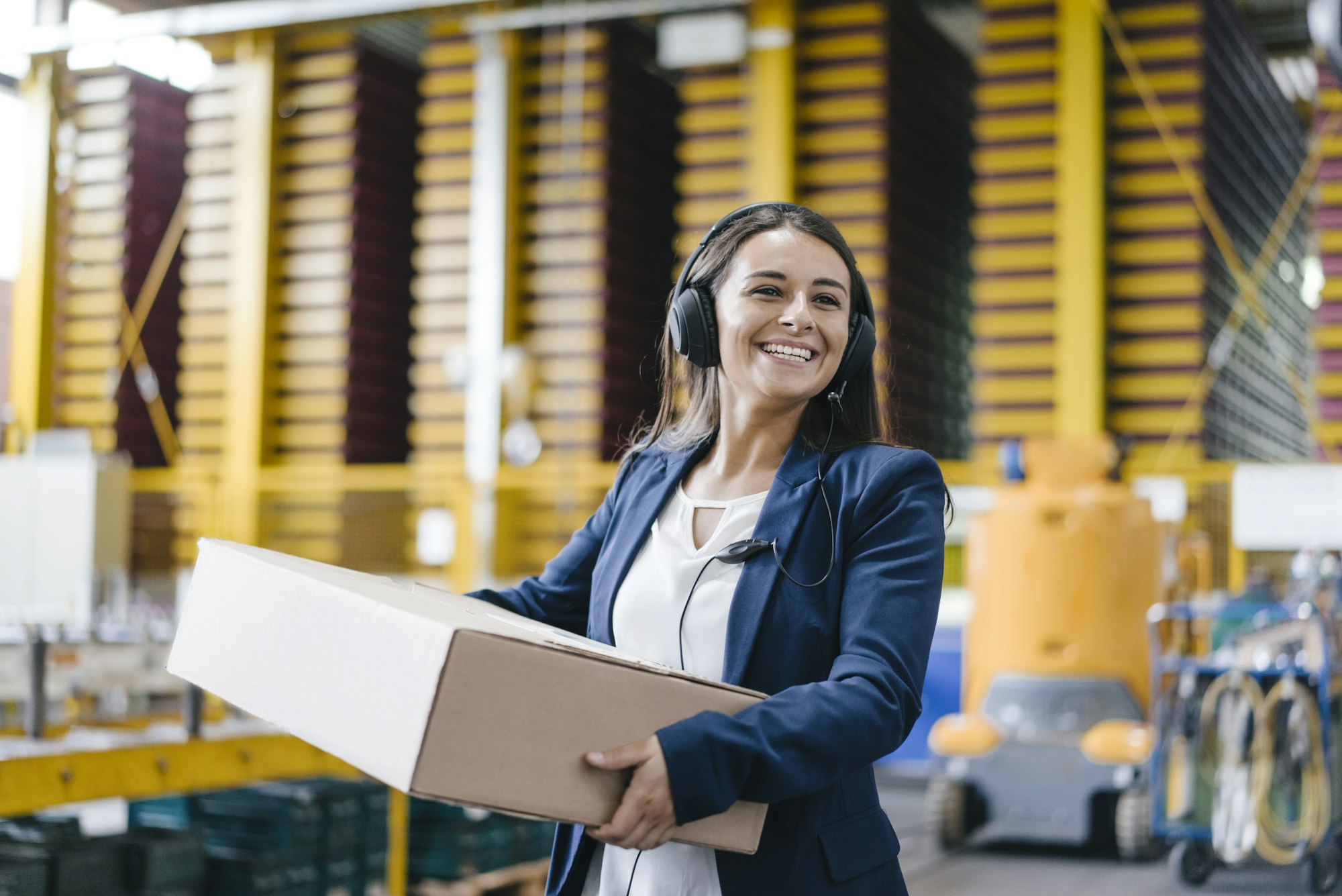 Young woman working at parcel service, carrying parcel in warehouse